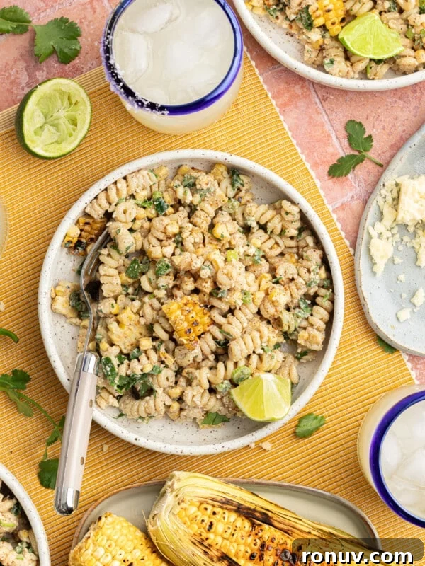 Creamy Jalapeño Popper Potato Salad with Bacon and Cheddar 11 Elote pasta salad topped with cotija cheese and cilantro, on a tablecloth with margaritas and limes for serving.
