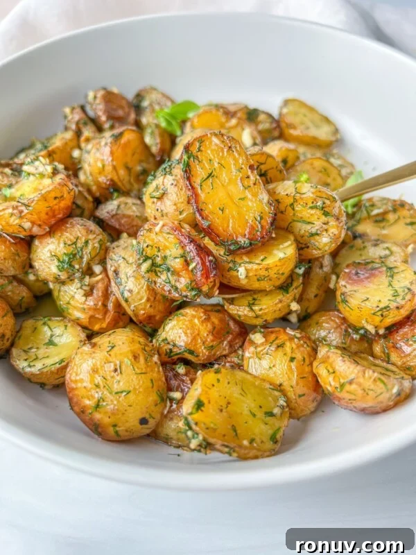 Roasted baby potatoes with herbs and crumbled feta in a white bowl.