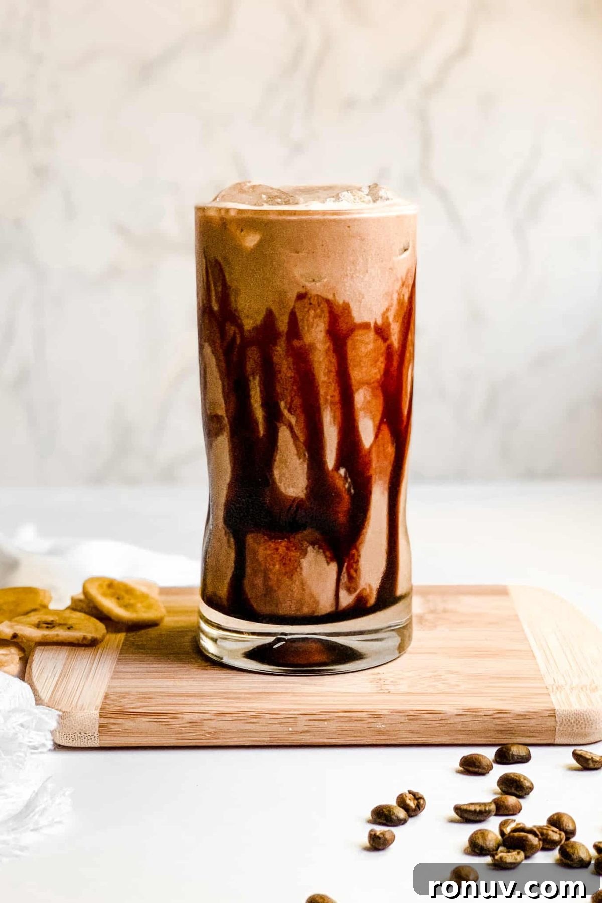 Iced Coffee Protein Smoothie with Chocolate Syrup Creamy Banana Coffee Smoothie in a Tall Glass with Coffee Beans and Sliced Bananas for Food Photography