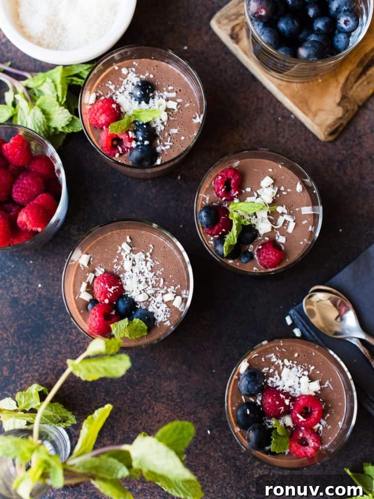 No-Bake Chocolate Hazelnut Mousse Recipe 4 Four glasses of Tofu Chocolate Hazelnut Mousse garnished with berries, coconut and white chocolate.