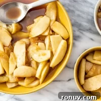 Baked apple slices in caramel sauce in yellow bowls.