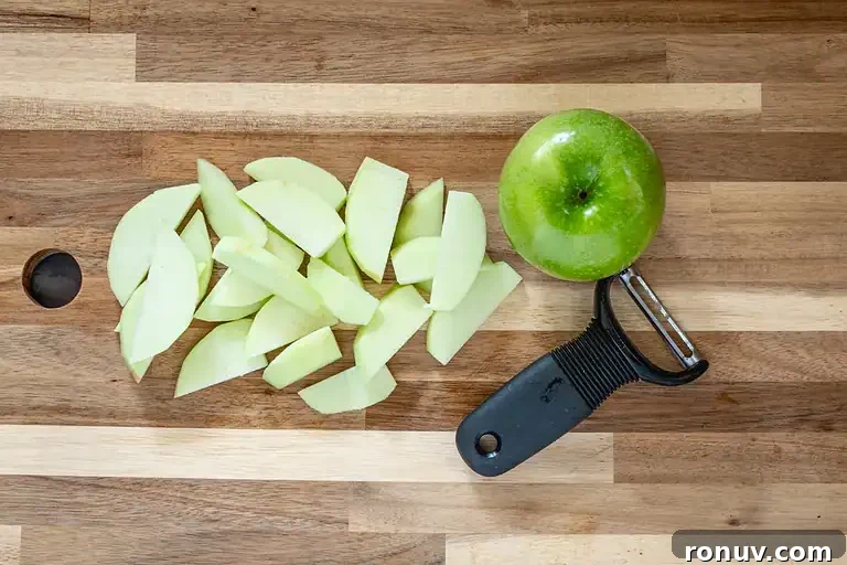 Warm Cinnamon-Baked Apples Recipe 4 Sliced green apple on wooden cutting board.