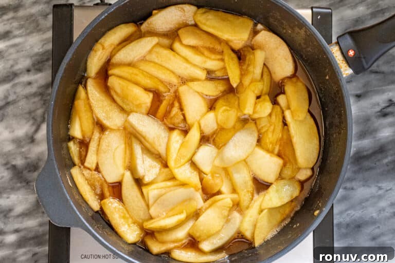 Warm Cinnamon-Baked Apples Recipe 6 Apples cooking in a skillet with butter and spices.