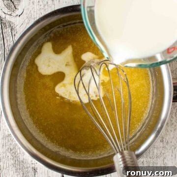 Ricotta-Stuffed Pasta Shells Recipe 5 Milk being poured into a butter mixture in a stainless steel pan with a whisk in it.