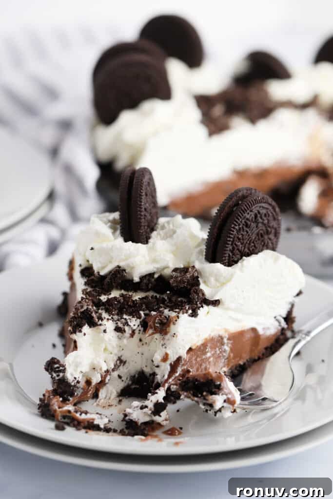 Classic Chocolate Cream Pie Recipe 6 A serving plate with a slice of chocolate cream pie topped with whipped cream and Oreo cookies.
