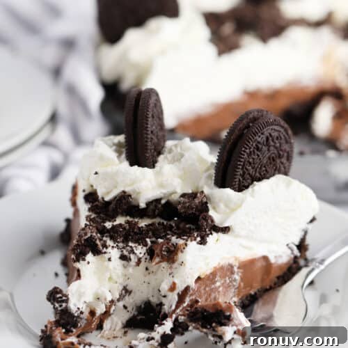 A white plate with a slice of chocolate cream pie topped with oreo cookies.