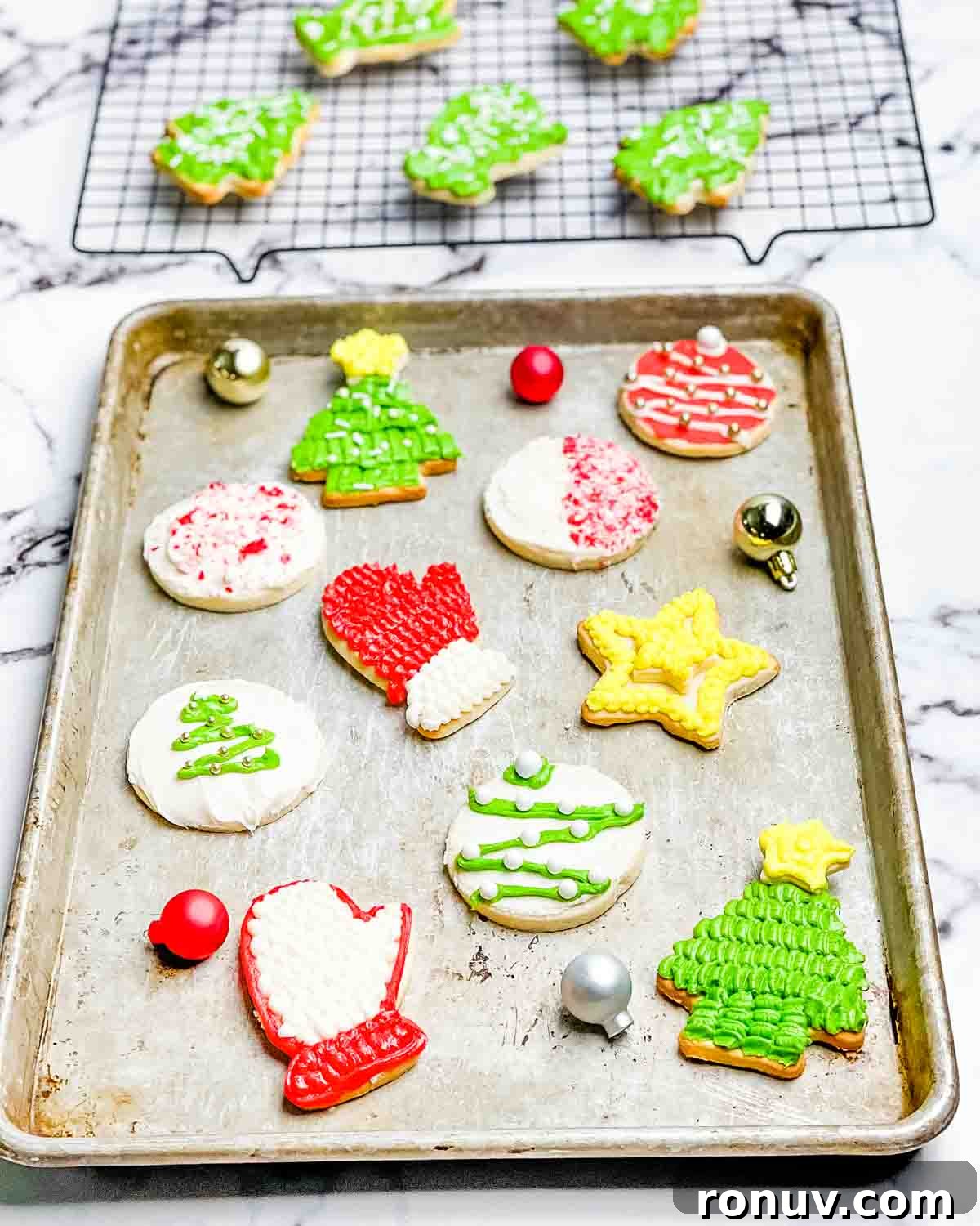 Air Fryer Sugar Cookies Recipe: Soft, Quick Homemade Treat 9 The decorated sugar cookies on a baking sheet, and in the background on a wire cooling rack.