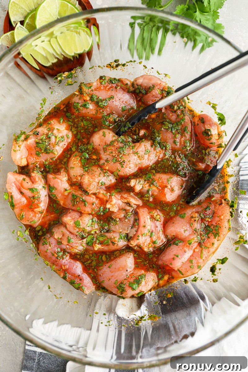A large mixing bowl filled with chicken thighs marinating in a honey lime cilantro marinade