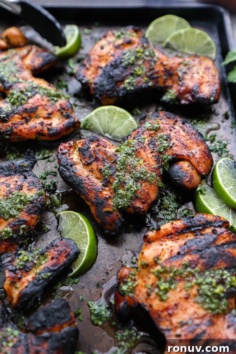 Grilled chicken thighs drizzled in a honey lime sauce sitting next to fresh lime wedges