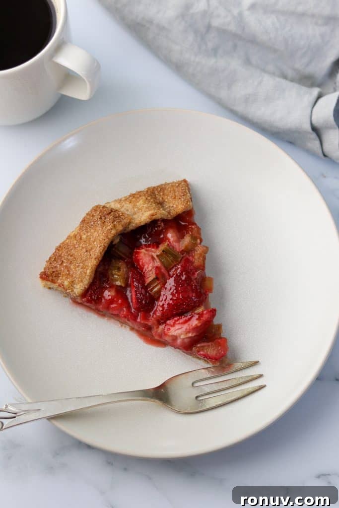 Rustic Strawberry Rhubarb Galette with Rye Crust 10 A slice of strawberry rhubarb galette on a plate with a fork