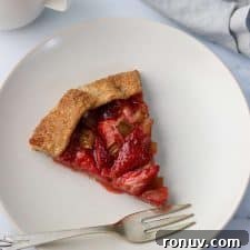 A slice of strawberry rhubarb galette on a plate with a fork