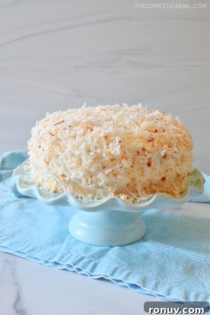 Moist Coconut Layer Cake with Coconut Buttercream 3 coconut layer cake on a blue cake stand