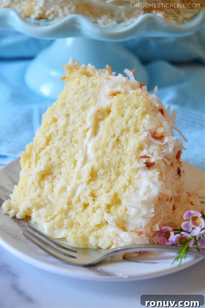 Moist Coconut Layer Cake with Coconut Buttercream 5 coconut layer cake slice with flowers and a fork on a plate