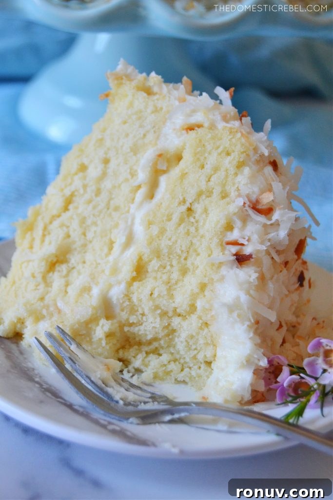 closeup of a slice of coconut layer cake with bite missing