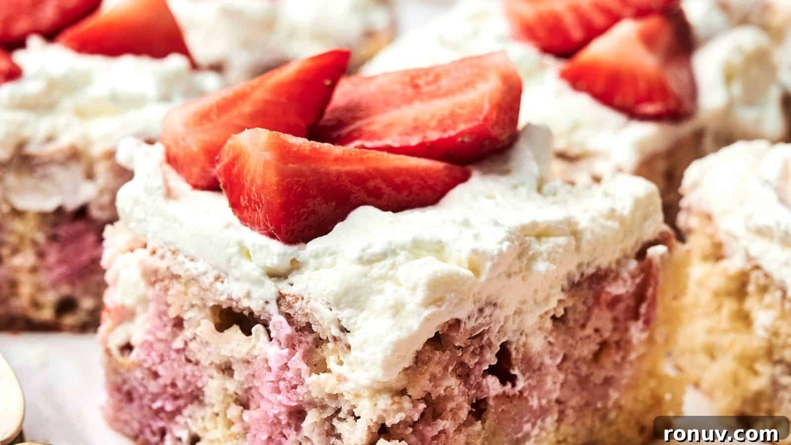 21 Strawberry Recipes to Savor Strawberry Season 19 A slice of cake with a light pink and beige interior, topped with white frosting and sliced strawberries.