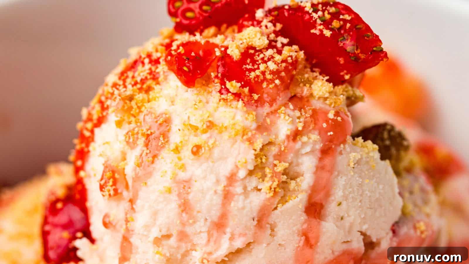 21 Strawberry Recipes to Savor Strawberry Season 9 Close-up of ice cream topped with strawberry pieces, strawberry sauce, and crumbled cookie or biscuit.