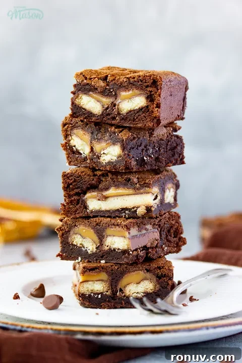 Homemade Fudgy Twix Brownies Recipe 6 A stack of Twix brownies on a white ribbed plate with a fork.