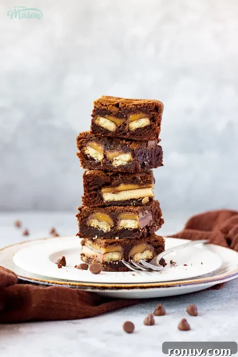 Homemade Fudgy Twix Brownies Recipe 8 A stack of Twix brownies displayed with a brown linen napkin.