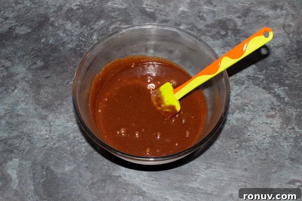 Homemade Fudgy Twix Brownies Recipe 11 Chocolate, eggs and sugar mixed together in a glass bowl with a spatula.