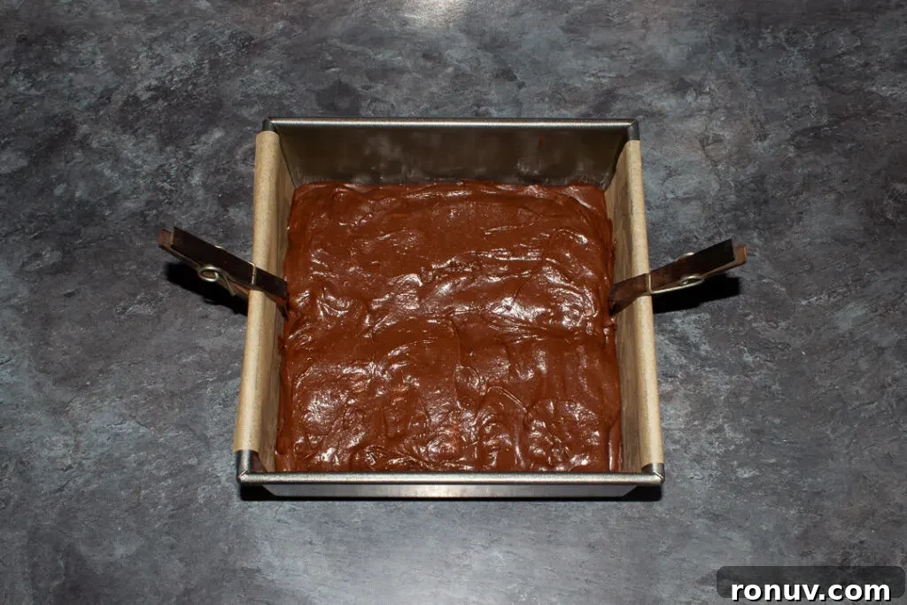 Homemade Fudgy Twix Brownies Recipe 14 Twix brownies in a lined square baking tin ready to be baked.