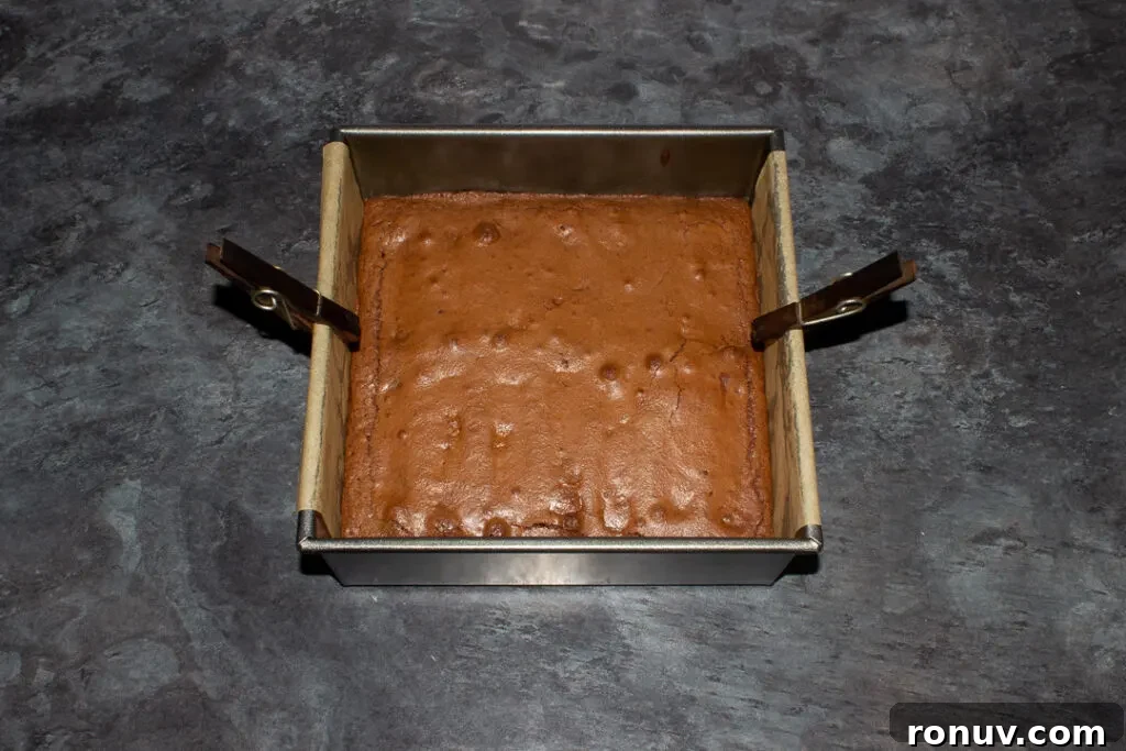Homemade Fudgy Twix Brownies Recipe 15 Baked Twix brownie in a lined square baking tin.