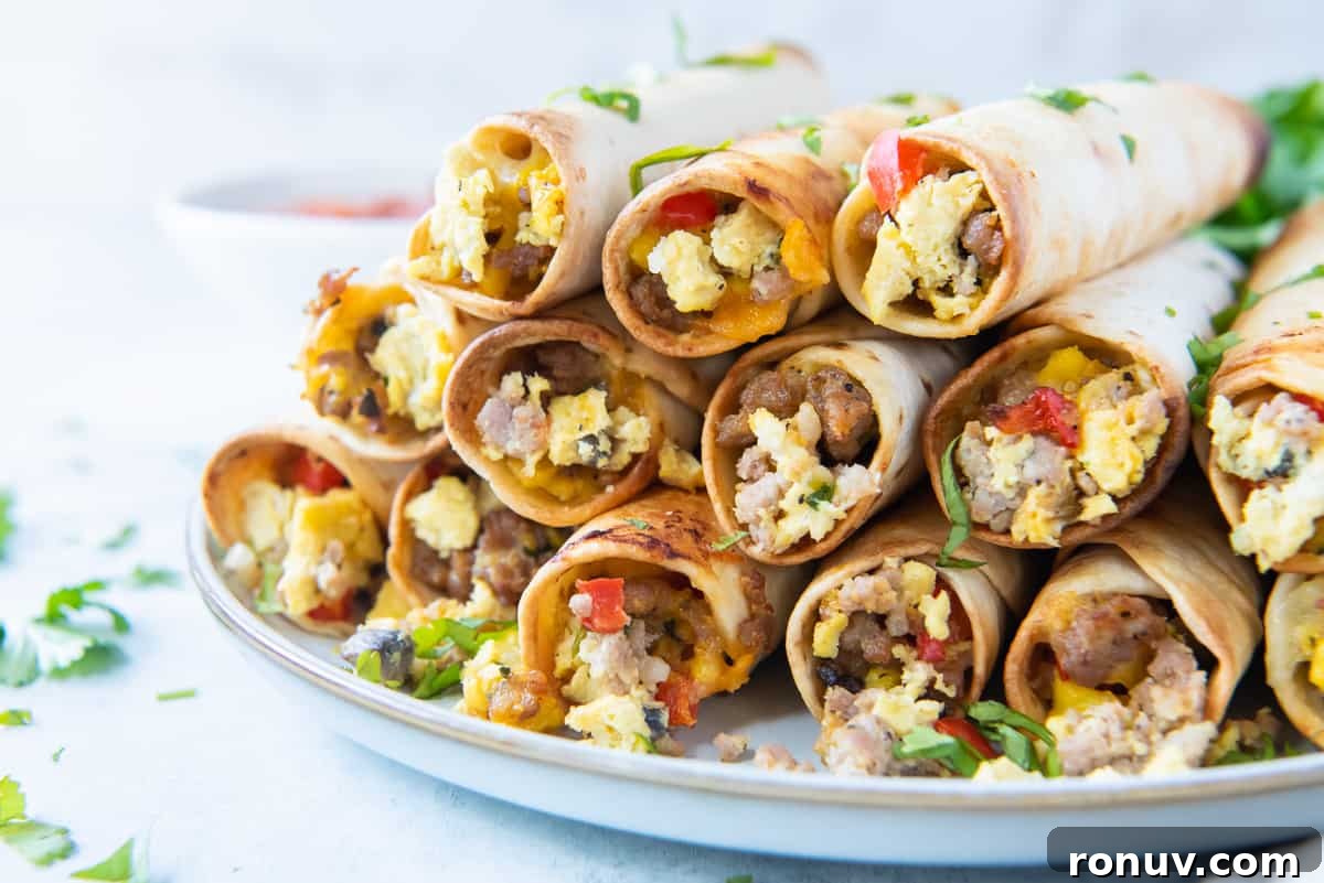 Crispy Oven-Baked Breakfast Taquitos Recipe 5 A stack of egg and sausage breakfast taquitos stacked on a white plate.