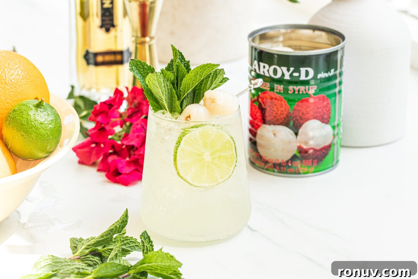 bowl of citrus, a glass of lychee cocktail spritz, can of lychees, st germain bottle