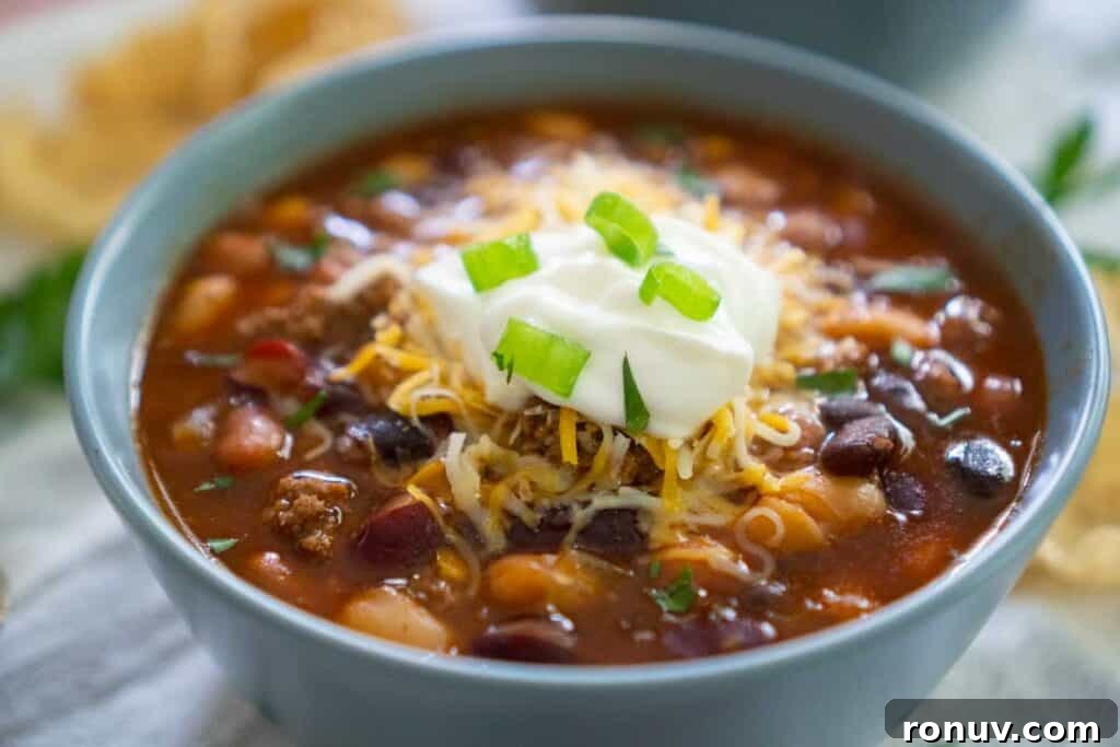 taco soup in blue bowl with sour cream and green onion