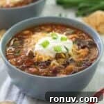 taco soup in a light blue bowl topped with sour cream and chopped green onion