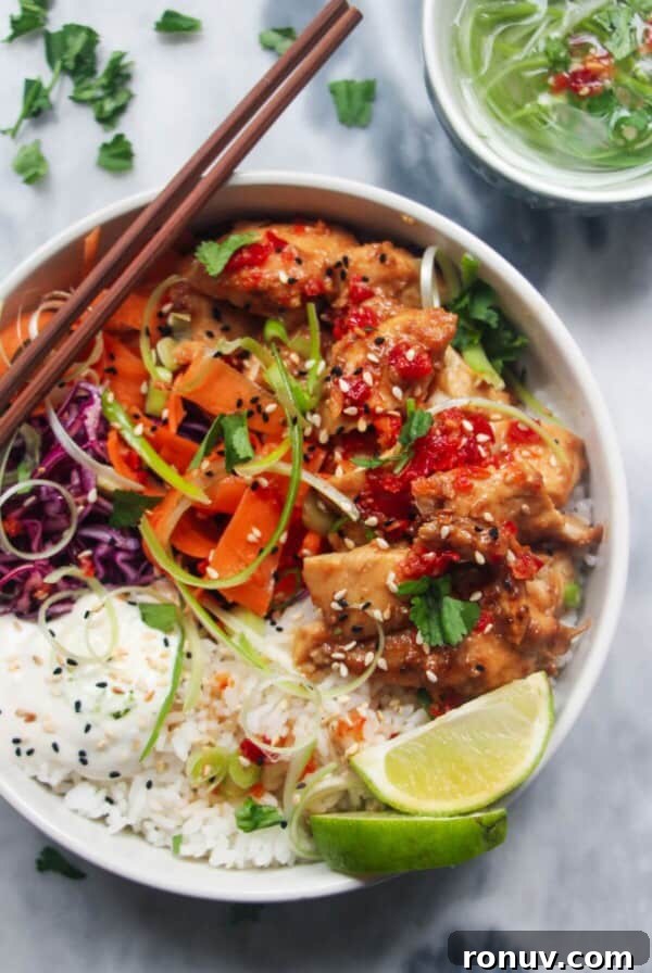 Chicken poke bowl on a grey marble background, with chopsticks on the side and a jar of dressing.