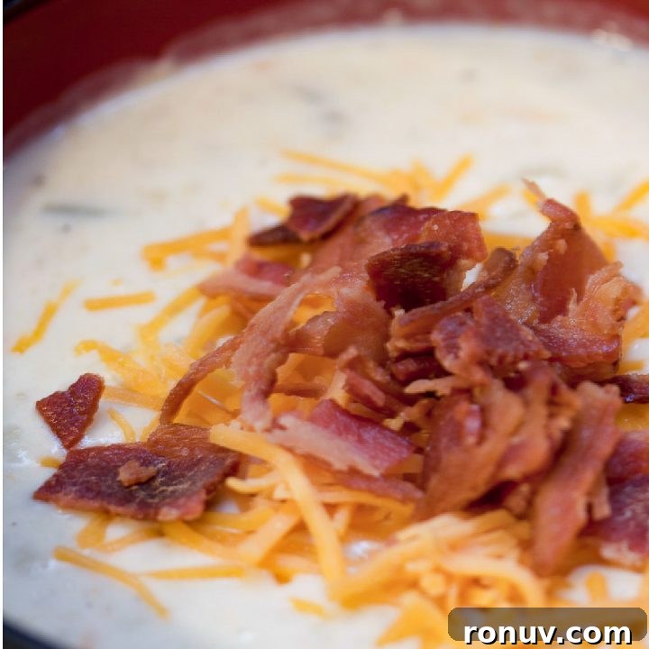 Baked potato soup topped with shredded cheddar cheese and chopped bacon.