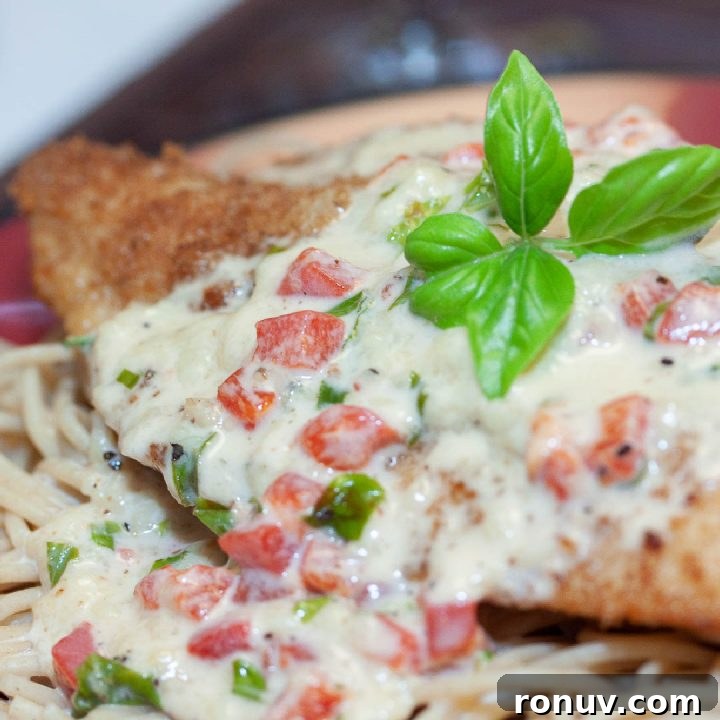 Breaded cooked chicken breast smothered in a cream sauce with basil and red peppers