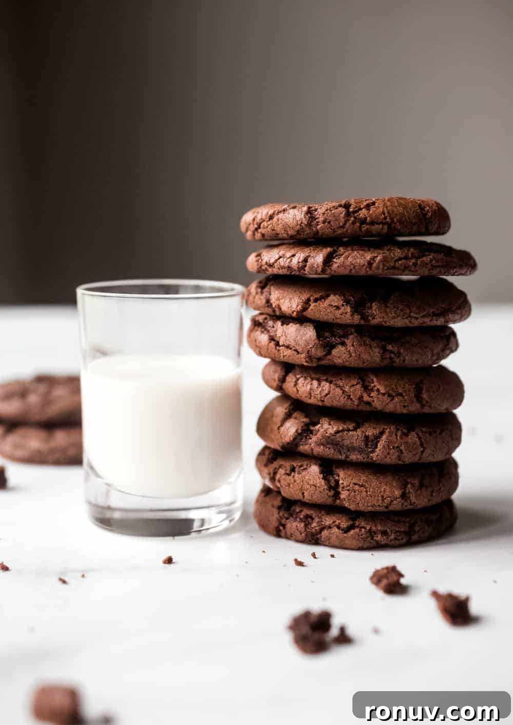 Side view of several mint chocolate cookies stacked next to a glass of milk