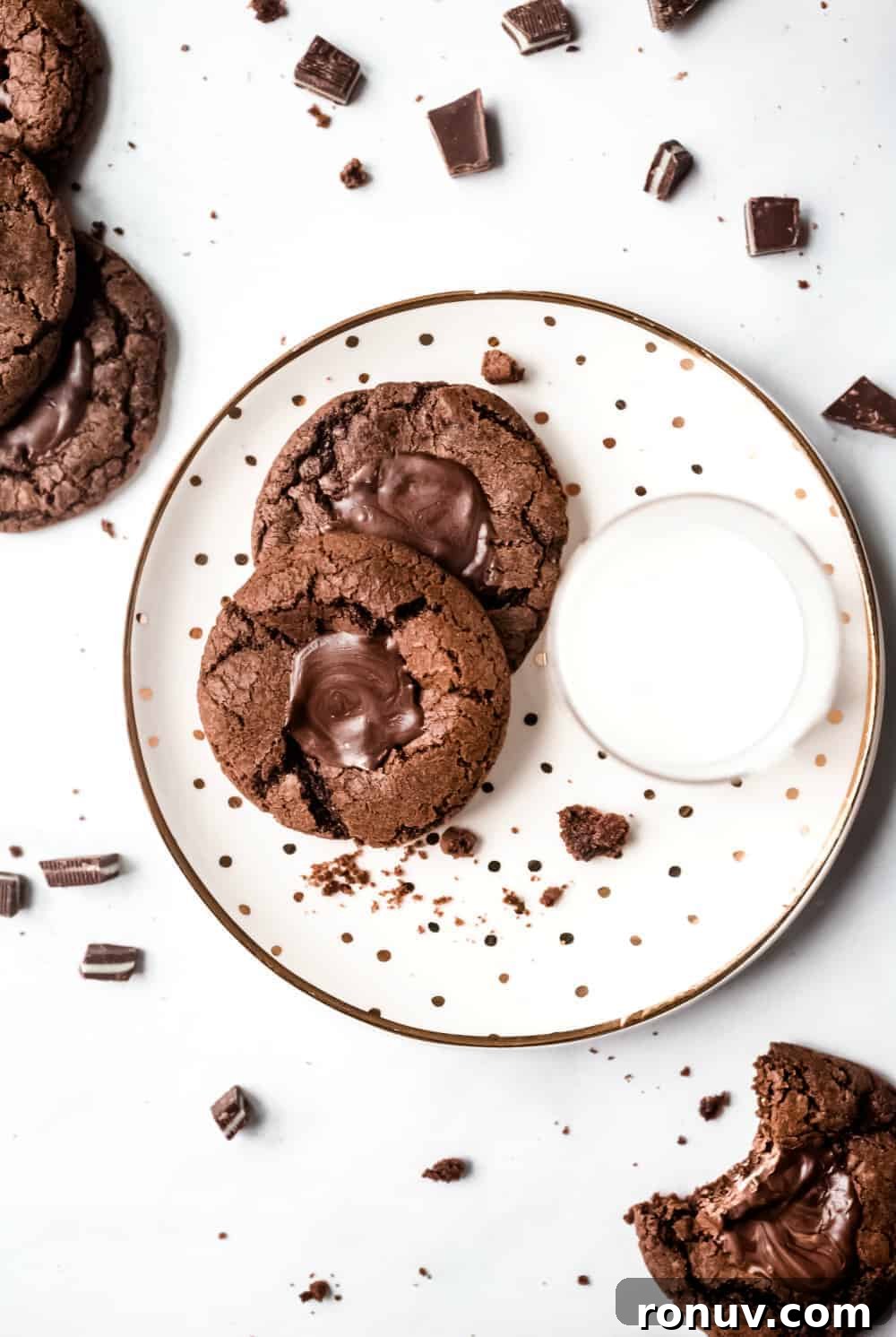 Two mint chocolate cookies on a white plate next to a glass of milk
