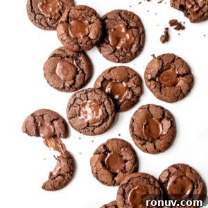 chocolate mint cookies scattered across a white surface, with some broken in half.