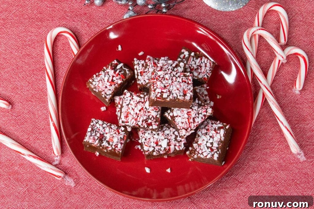 No-Bake Chocolate Peppermint Fudge Recipe 5 Peppermint fudge on a red plate with scattered candy canes.