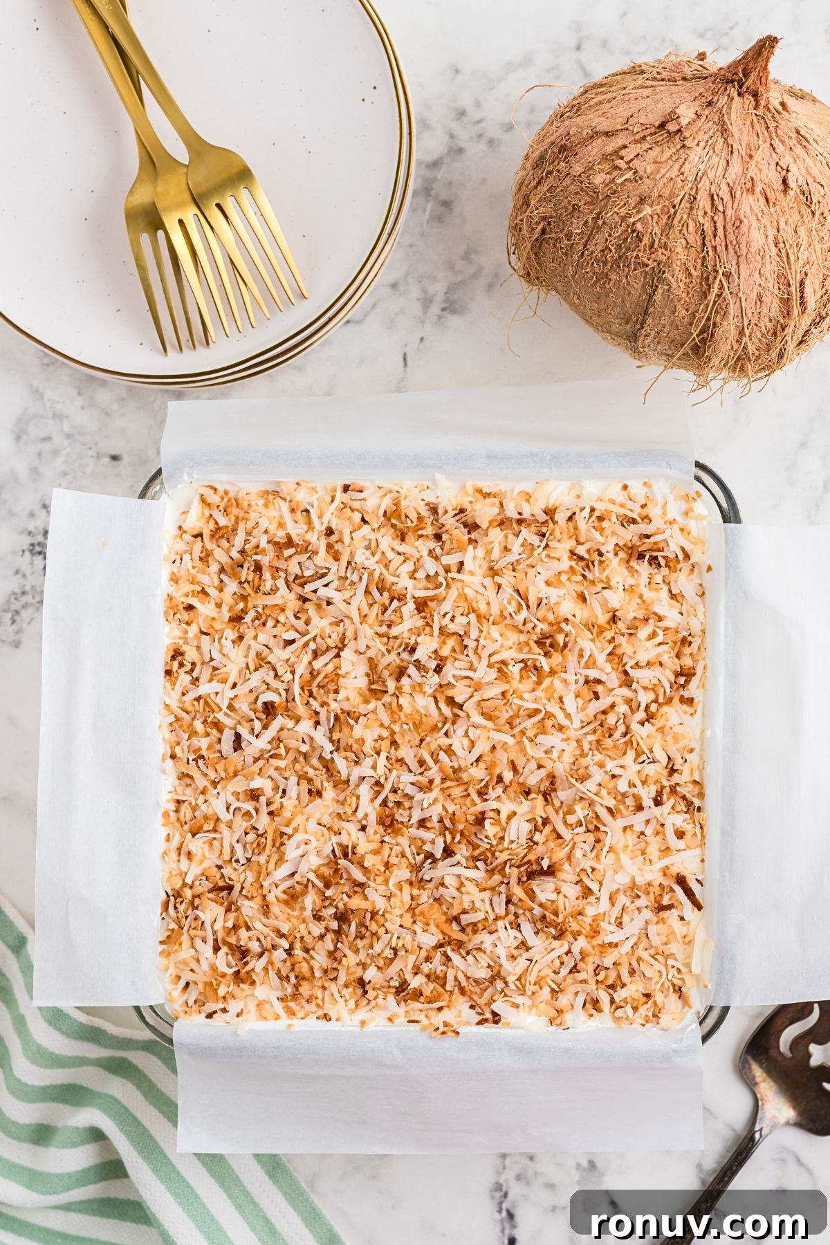 Homemade Coconut Delight Dessert Recipe 7 Coconut delight dessert topped with toasted coconut on a marble table.