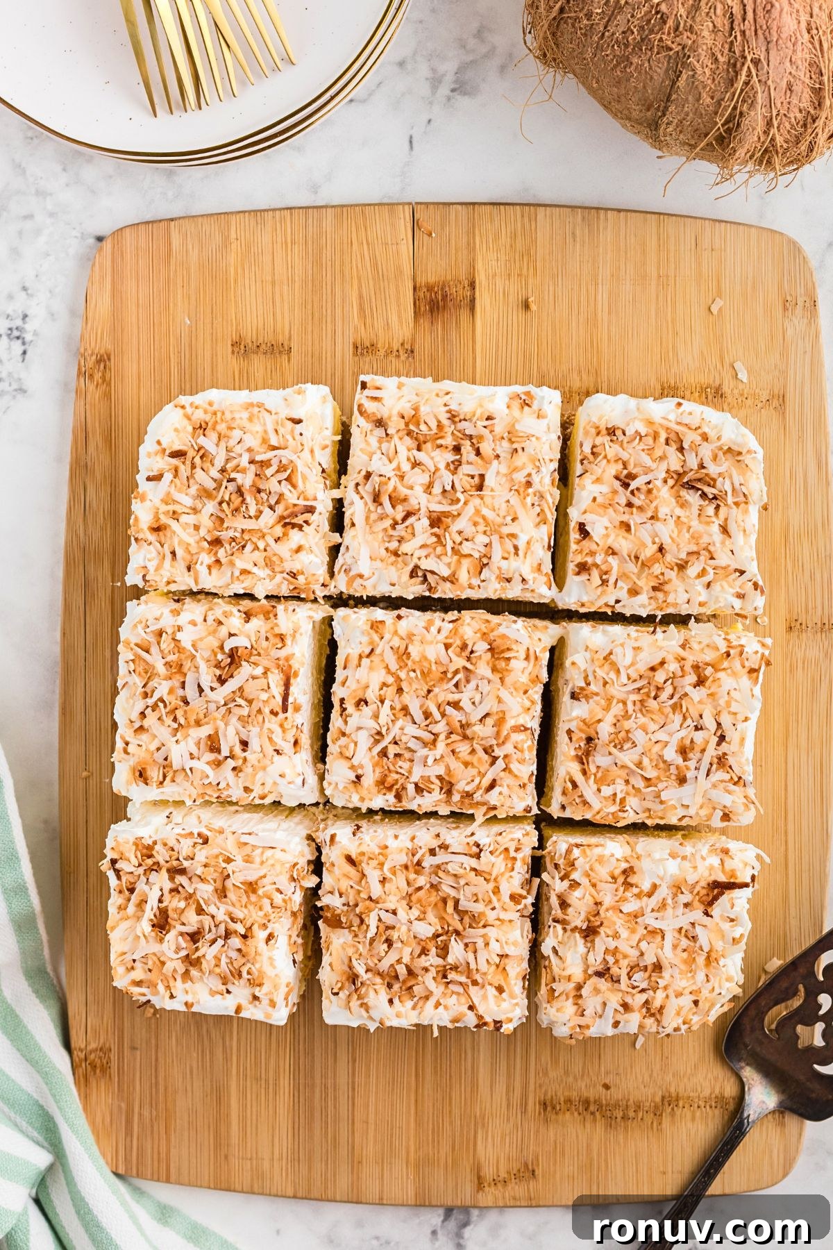 Homemade Coconut Delight Dessert Recipe 8 Coconut delight dessert on a wooden cutting board, cut into slices.