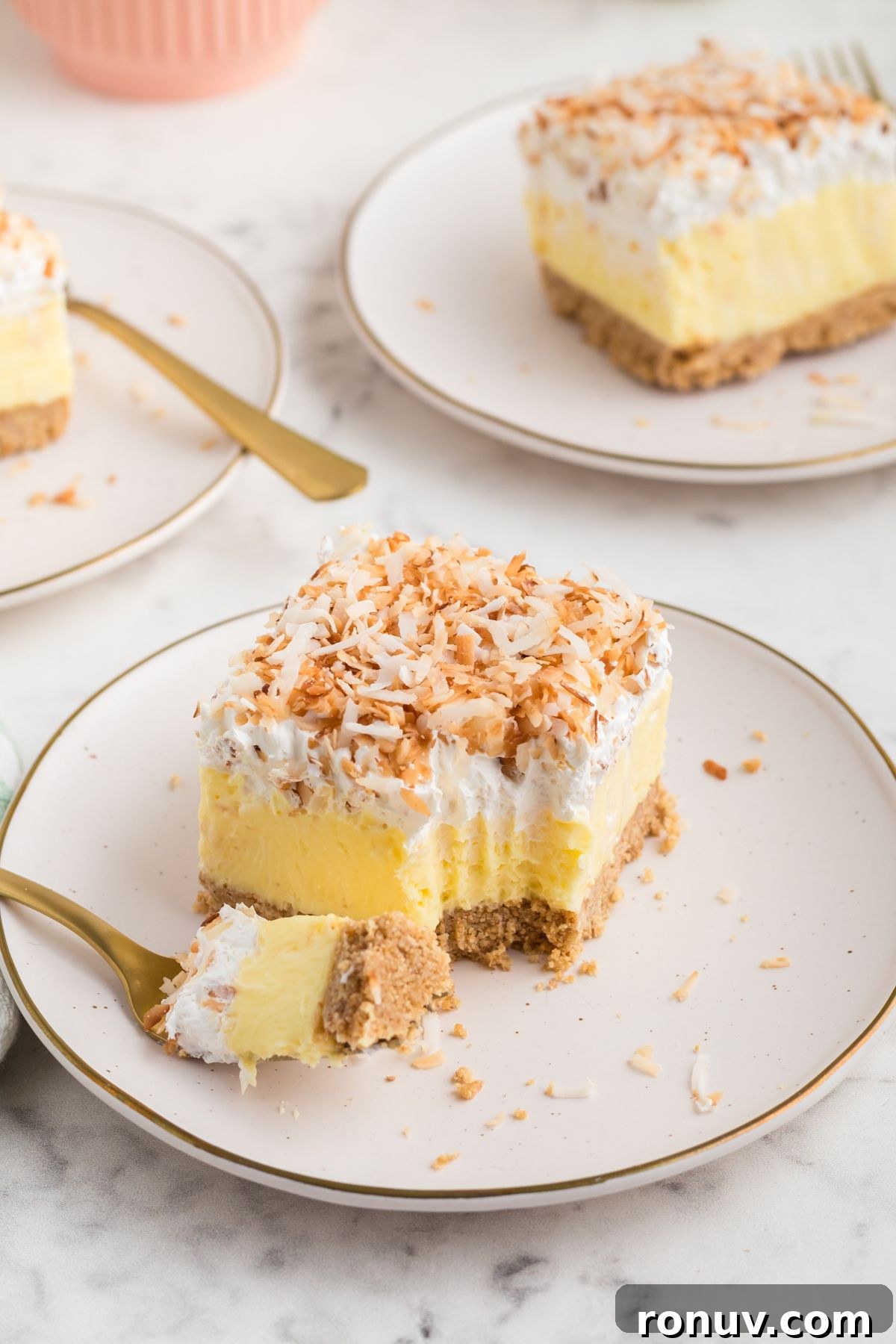 Homemade Coconut Delight Dessert Recipe 9 A slice of coconut delight on a small white plate with a fork on the side.