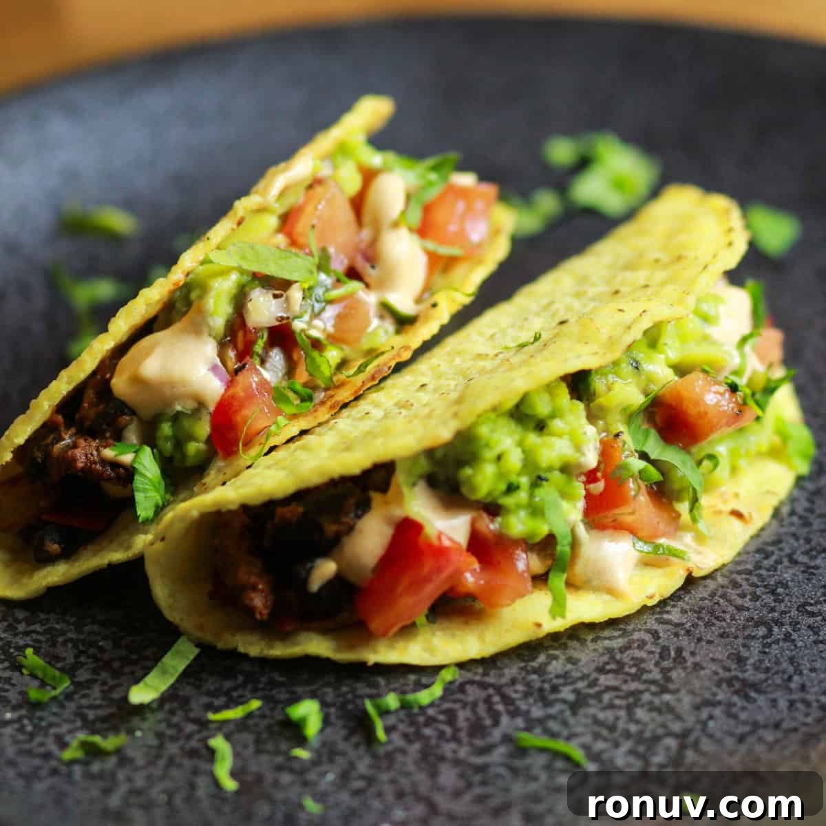 Image of two loaded black bean tacos on a black plate.