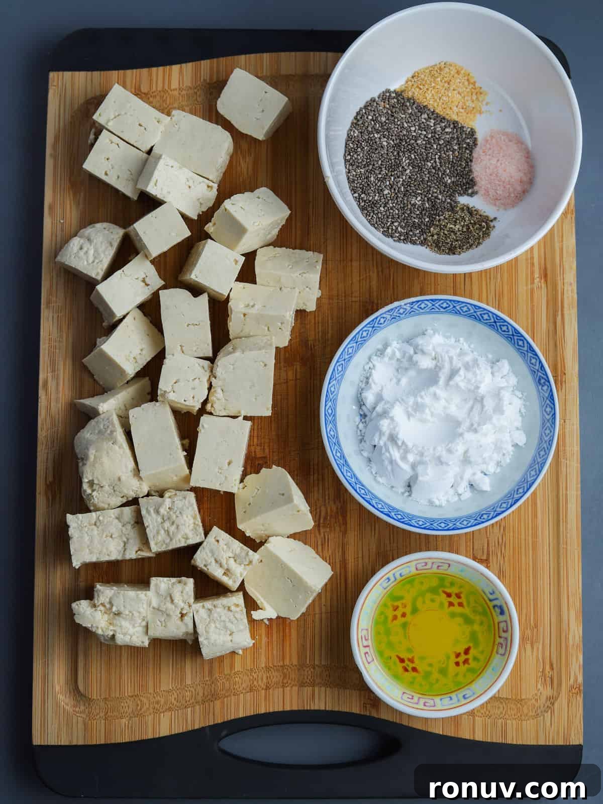 Crispy Air Fryer Tofu Recipe with Chia Seeds 5 image of crispy chia tofu ingredients showing chopping board with cubes of raw tofu and three bowls showing the ingredients.