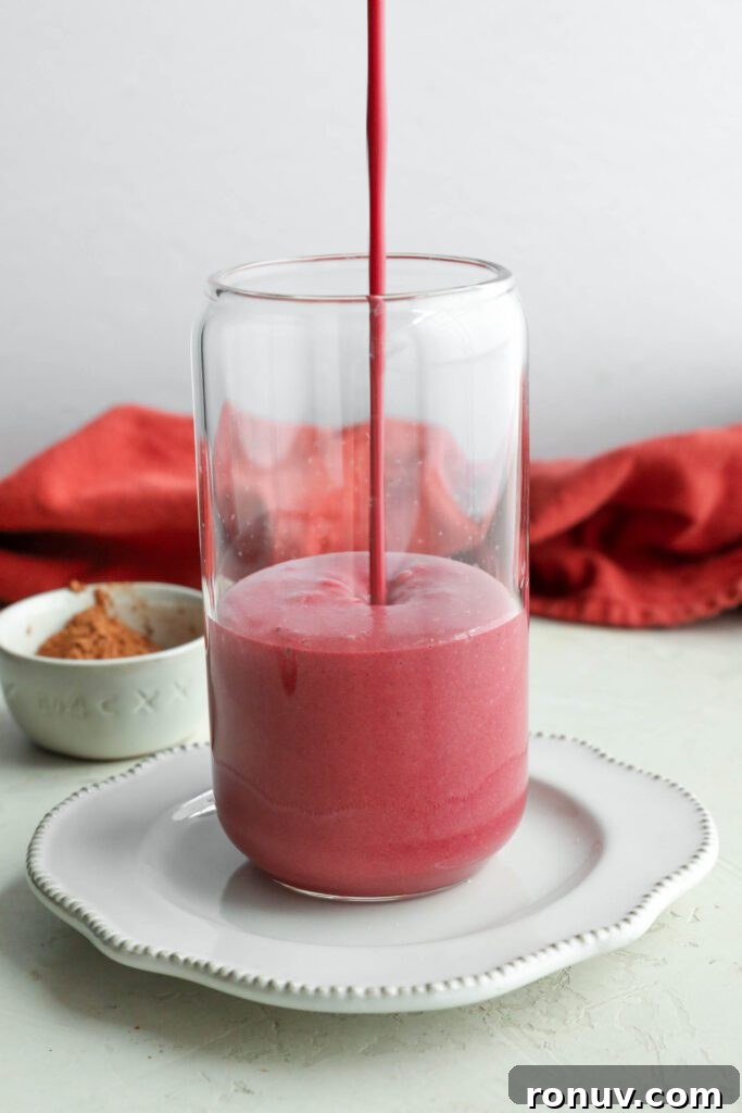 Creamy Red Velvet Protein Shake Recipe 7 Red Velvet Protein Shake pouring into glass with red towel in background by Flora & Vino