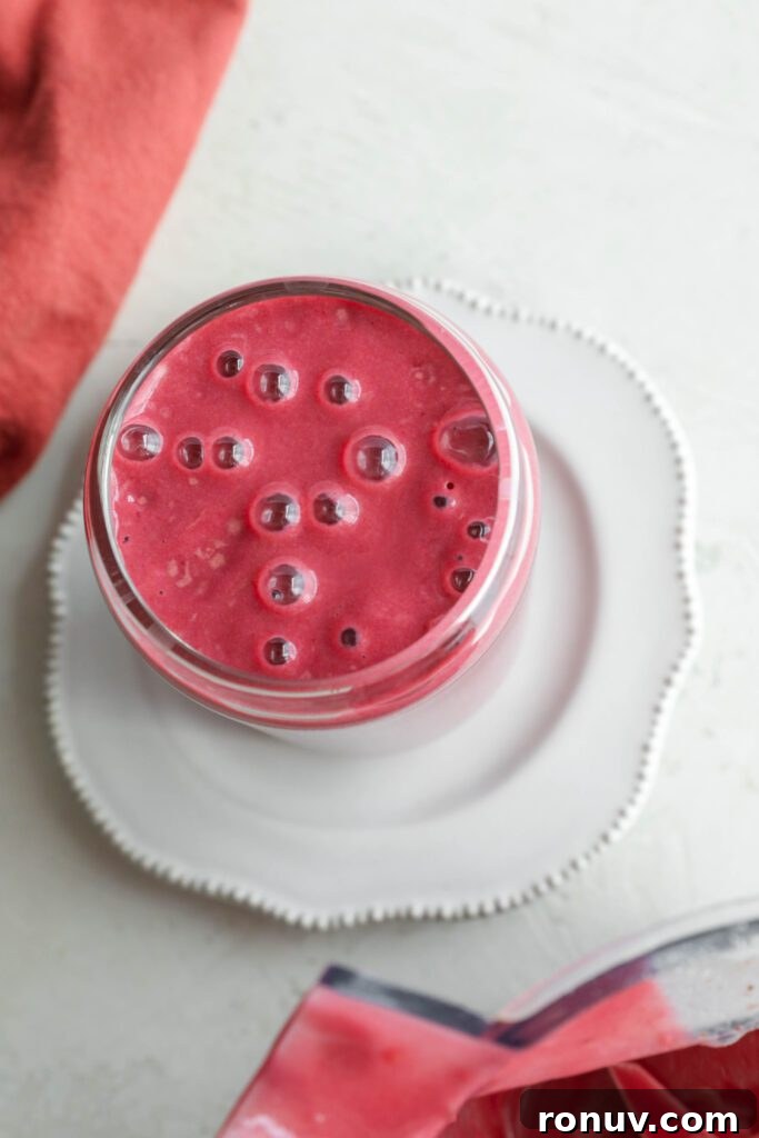 Creamy Red Velvet Protein Shake Recipe 8 Red Velvet Protein Shake in glass with bubbles and red towel on side by Flora & Vino