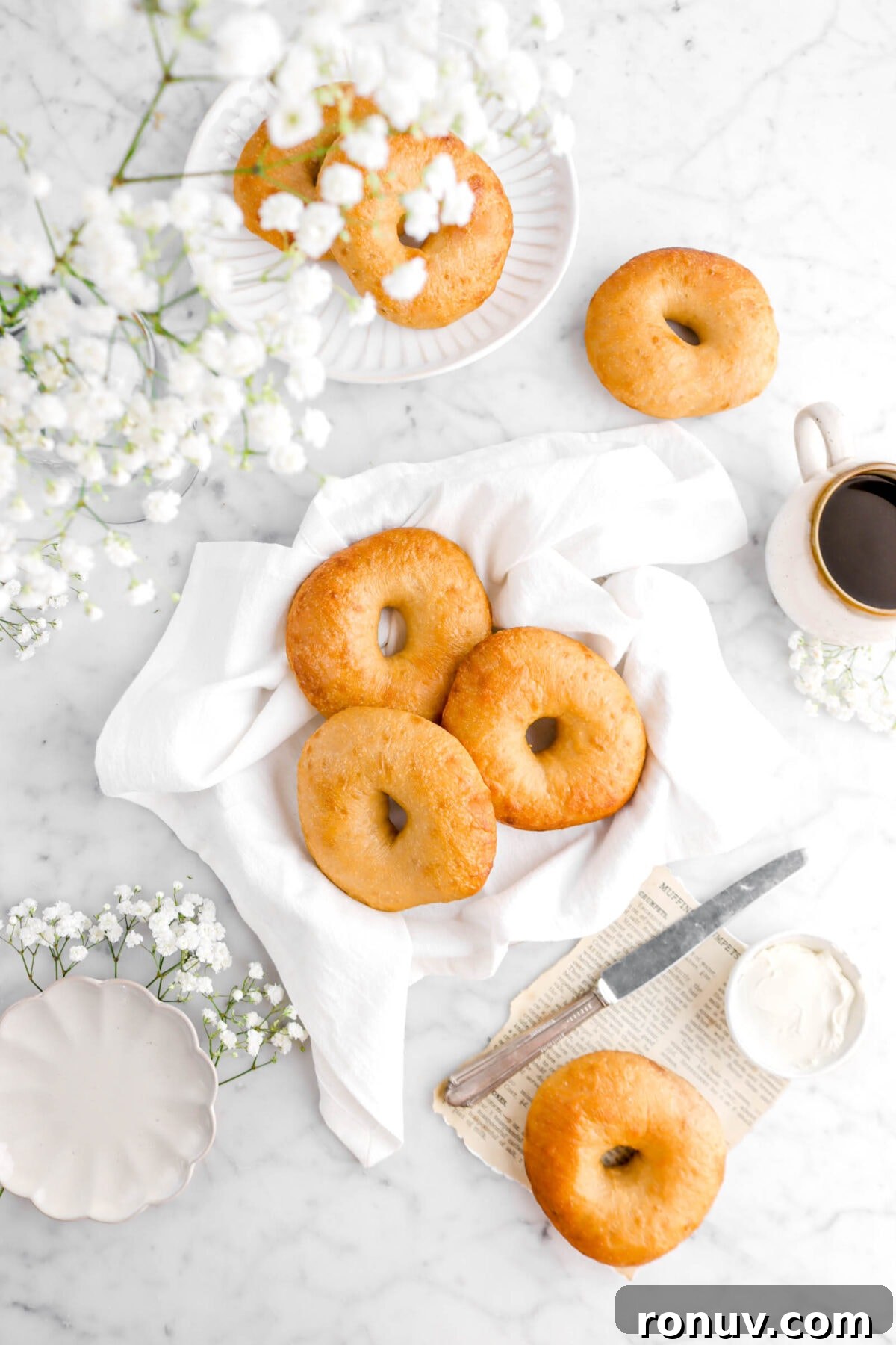 How to Make Sourdough Bagels at Home 10 three bagels on white napkin with flowers and other bageks around