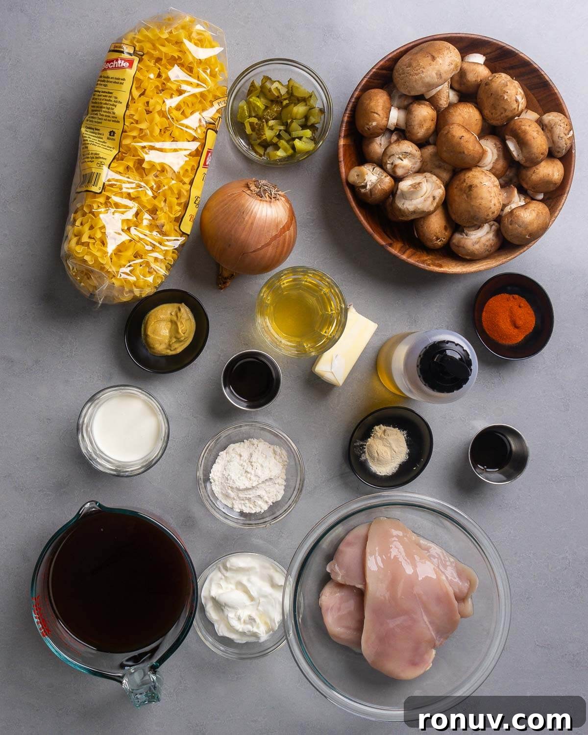Creamy Chicken Stroganoff with Mushrooms and Egg Noodles 3 Ingredients shown: egg noodles, pickles, onion, mushrooms, Dijon mustard, wine, worcestershire sauce, butter, olive oil, paprika, garlic powder, chicken stock, flour, sour cream, heavy cream, and chicken breasts.