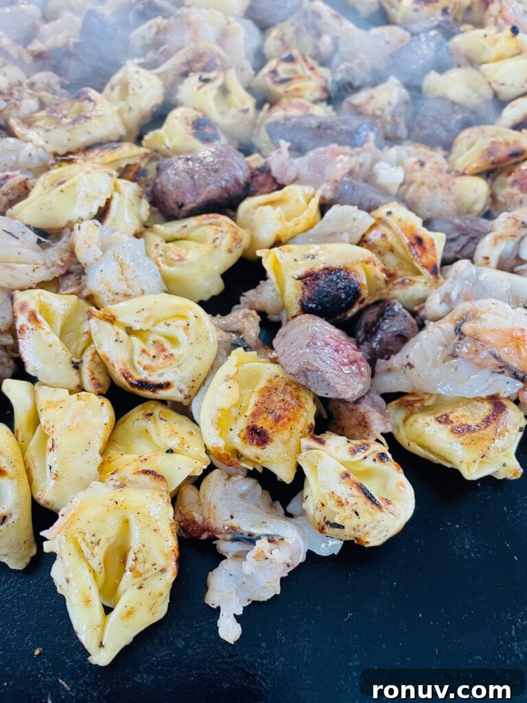 Blackstone Griddle Surf and Turf Tortellini Recipe 6 adding steak to tortellini on griddle
