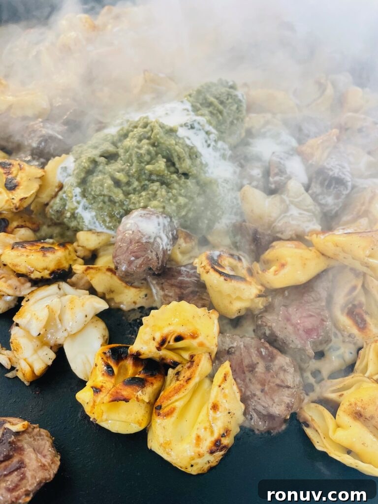 Blackstone Griddle Surf and Turf Tortellini Recipe 8 adding pesto to Blackstone Surf and Turf Tortellini