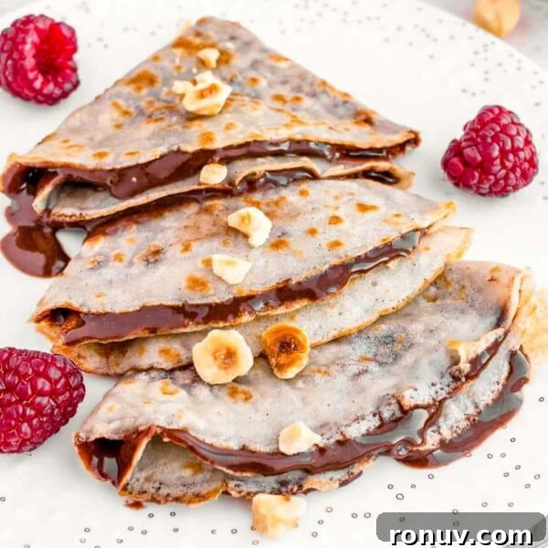 Vegan French Toast Recipe with Cinnamon Maple Syrup 14 vegan crepes on a white plate with hazelnuts and berries