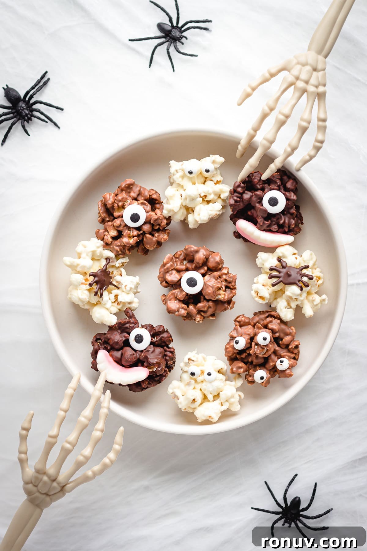 How to Make Chocolate Halloween Popcorn Balls 2 Bowl of Halloween chocolate popcorn balls with skeleton hands reaching in and fake spiders around the bowl.