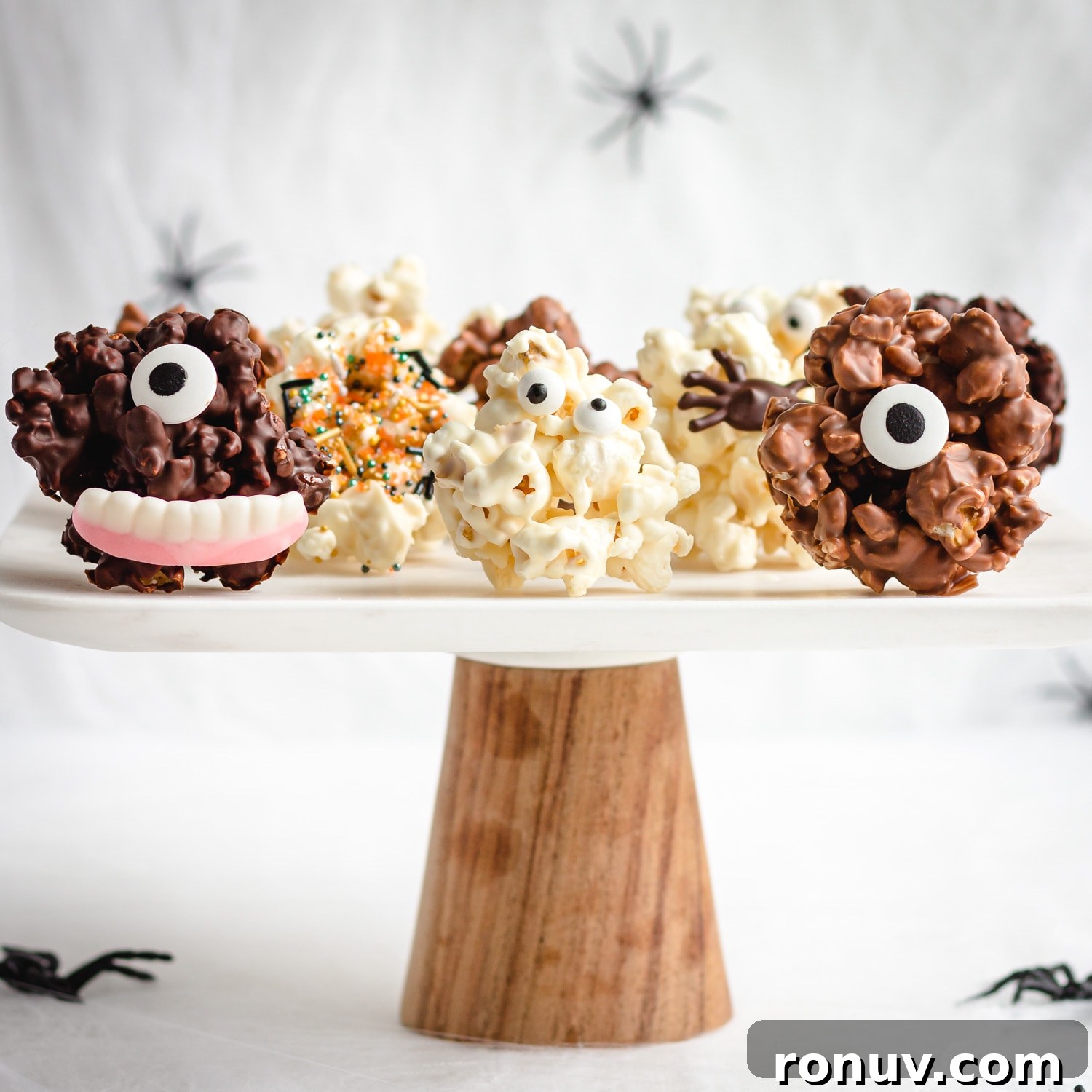 How to Make Chocolate Halloween Popcorn Balls 10 Cake stand with a variety of different Halloween popcorn balls on it.